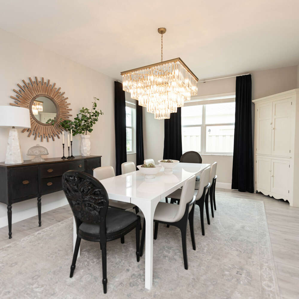 Light walls dining room-White dining table with dark chairs-dark curtains-dark furtinure-gold frame circle shape mirror-ashen wood floor-ceiling hanging lamp